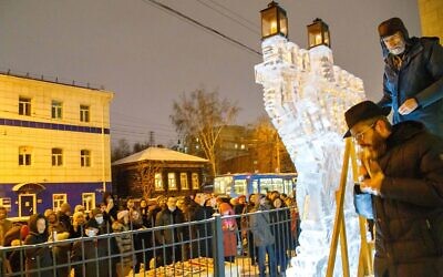 Rabbi Levy Kaminetsky, bottom right, prepares to light a Hanukkah menorah made of ice outside his synagogue in Tomsk, Russia on Nov. 28, 2021. (Courtesy/Levy Kaminetsky via JTA)