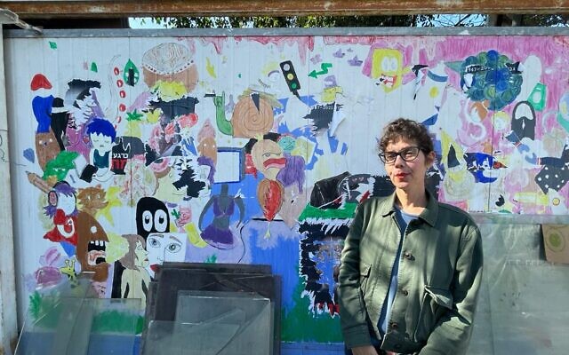 Ronit Aldouby stands in front of the gate to her Givat Amal home, November 23, 2021. (Carrie Keller-Lynn/Times of Israel)