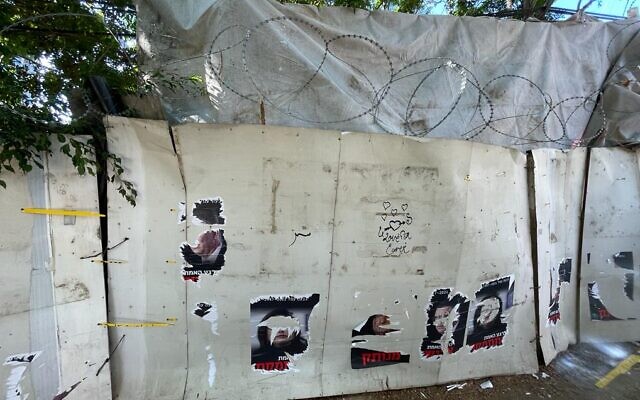 Self-constructed wall bordering Ronit Aldouby's Givat Amal home, with torn protest posters, on November 23, 2021. (Carrie Keller-Lynn/Times of Israel)