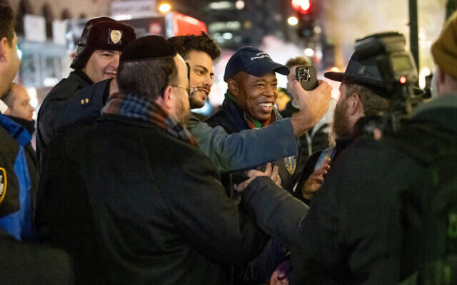 New York City Mayor-Elect Eric Adams, center, takes photos with people celebrating the first night of Hanukkah at Grand Army Plaza in Brooklyn, Nov. 28, 2021. (Alexi Rosenfeld/Getty Images via JTA)