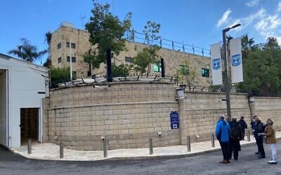 A group of Israelis read the plaque on the wall of Beit Aghion, the official Prime Minister's Residence, Jerusalem, December 24, 2021 (David Horovitz / Times of Israel)