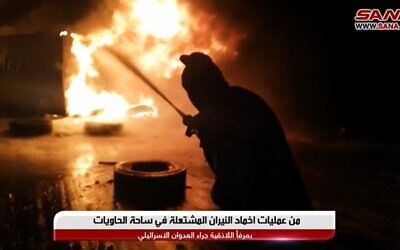 A Syrian fireman works to extinguish a fire caused by an alleged Israeli airstrike on the port of Latakia on December 28, 2021 (Screencapture/YouTube)