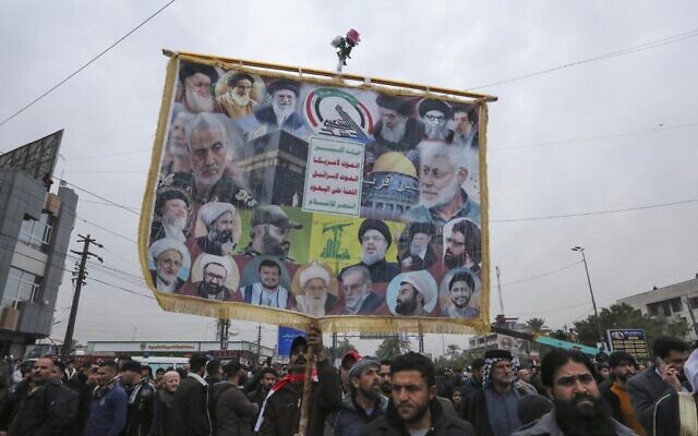 A man lifts an anti-US and anti-Israel placard as members and supporters of Iraq's al-Hashed al-Shaabi ex-paramilitary alliance take part in a demonstration and a symbolic funeral for Qasem Soleimani and Abu Mahdi al-Muhandis in Baghdad, on January 1, 2022. (Sabah Arar/AFP) A man lifts an anti-US and anti-Israel placard as members and supporters of Iraq's al-Hashed al-Shaabi ex-paramilitary alliance take part in a demonstration and a symbolic funeral for Qasem Soleimani and Abu Mahdi al-Muhandis in Baghdad, on January 1, 2022. (Sabah Arar/AFP)