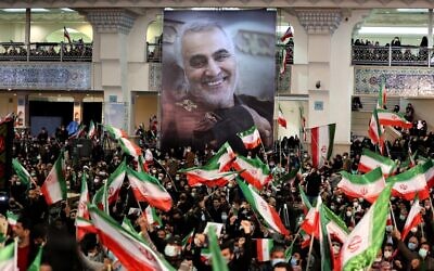 Iranians lift national flags during a ceremony in the capital Tehran, on January 3, 2022, commemorating the second anniversary of the killing in Iraq of top Iranian commander Qassem Soleimani (portrait) and Iraqi commander Abu Mahdi al-Muhandis in a US raid. (Atta Kenare/AFP)