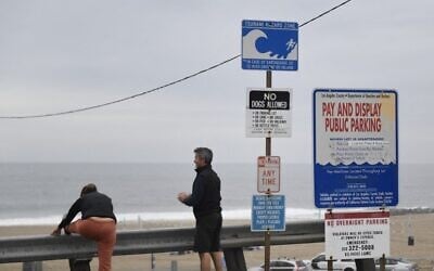 People stretch next to a tsunami hazard zone sign in El Segundo, California, on January 15, 2022. (Patrick T. Fallon/AFP)