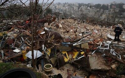 A person walks on the ruins of a Palestinian house demolished by Israeli authorities in Jerusalem's Sheikh Jarrah neighborhood on January 19, 2022 (Ahmed Gharabli/AFP)