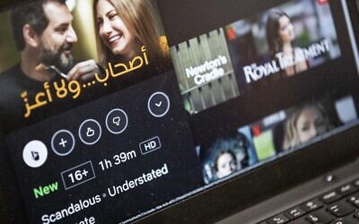 This picture taken on January 23, 2022, in Cairo shows a laptop displaying a scene from the Netflix-produced pan-Arab film 'Ashab wala Aaz' depicting Lebanese actors Adel Karam and Diamand Bou Abboud. (Khaled Desouki/AFP)