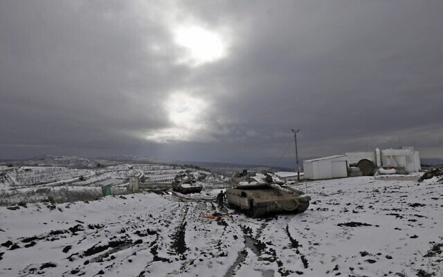 Israel soldiers stand near a Merkava IV battle tank parked in a military post near the Syria border in the Israeli-annexed Golan Heights on January 24, 2022. (JALAA MAREY / AFP) Israel soldiers stand near a Merkava IV battle tank parked in a military post near the Syria border in the Israeli-annexed Golan Heights on January 24, 2022. (JALAA MAREY / AFP)