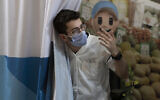 A medical professional with Clalit Health Services waves in his next patient to receive a coronavirus vaccine booster shot, at the Cinema City complex in Jerusalem, Monday, Aug. 30, 2021. (AP Photo/Maya Alleruzzo)