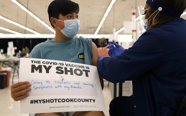 Lucas Kittikamron-Mora, 13, holds a sign in support of COVID-19 vaccinations as he receives his first Pfizer vaccination at the Cook County Public Health Department, May 13, 2021 in Des Plaines, Ill. (AP Photo/Shafkat Anowar, file)