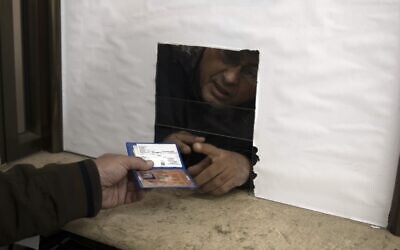 A Palestinian man hands over his temporary ID to a civil affairs employee to get his officially approved register letter, in Gaza City, January 3, 2022. (AP Photo/ Khalil Hamra)
