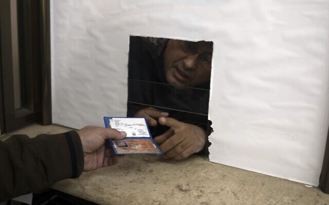 A Palestinian man hands over his temporary ID to a civil affairs employee to get his officially approved register letter, in Gaza City, January 3, 2022. (AP Photo/ Khalil Hamra) A Palestinian man hands over his temporary ID to a civil affairs employee to get his officially approved register letter, in Gaza City, January 3, 2022. (AP Photo/ Khalil Hamra)