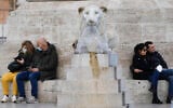 People sit by the Rome's Piazza del Popolo Lions fountain, Wednesday, Jan. 5, 2022 (AP Photo/Gregorio Borgia)