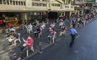 Workers wear face masks and practice social distancing while they wait to be tested for the coronavirus at Khaosan road in Bangkok, Thailand, on January 6, 2022. (Vichan Poti/AP)