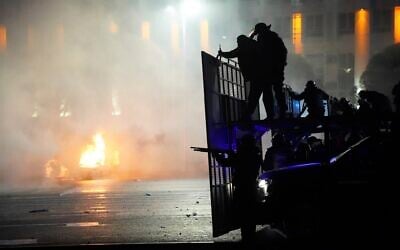 A police car on fire as riot police prepare to stop protesters in the center of Almaty, Kazakhstan, January 5, 2022. (AP Photo/Vladimir Tretyakov)