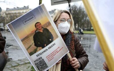 A woman holds a photo of Benjamin Briere during a rally in Paris, France, on Saturday, January 8, 2022. (AP/Adrienne Surprenant)