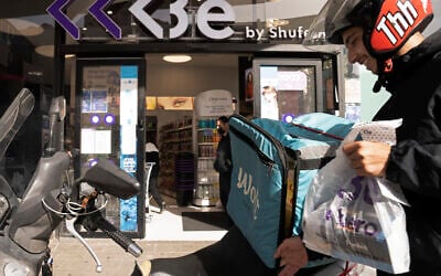 A delivery driver from the Wolt app leaves a pharmacy with rapid antigen tests for the coronavirus, to deliver to a customer in Tel Aviv, January 10, 2022. (AP Photo/Maya Alleruzzo)