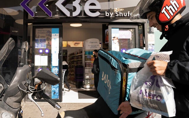 A delivery driver from the Wolt app leaves a pharmacy with rapid antigen tests for the coronavirus, to deliver to a customer in Tel Aviv, January 10, 2022. (AP Photo/Maya Alleruzzo) A delivery driver from the Wolt app leaves a pharmacy with rapid antigen tests for the coronavirus, to deliver to a customer in Tel Aviv, January 10, 2022. (AP Photo/Maya Alleruzzo)