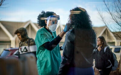 Maya Goode, a COVID-19 technician, performs a test on Jessica Sanchez outside Asthenis Pharmacy in Providence, Rhode Island, December 7, 2021. (AP Photo/David Goldman, File)