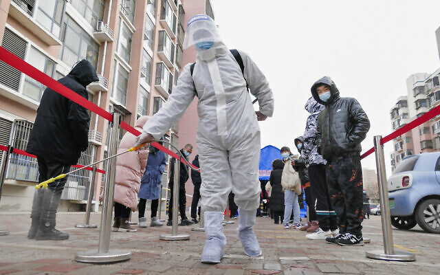 A worker wearing a protection suit sprays disinfectant as residents wearing face masks to protect from the coronavirus line up for the coronavirus test during a mass testing in north China's Tianjin municipality, on Sunday, January 9, 2022. (Chinatopix via AP) A worker wearing a protection suit sprays disinfectant as residents wearing face masks to protect from the coronavirus line up for the coronavirus test during a mass testing in north China's Tianjin municipality, on Sunday, January 9, 2022. (Chinatopix via AP)