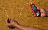 Vivek Shandas, a professor of climate adaptation at Portland State University, takes a temperature reading of almost 106 degrees in downtown Portland, Oregon, on August 12, 2021. (AP Photo/Nathan Howard, File)