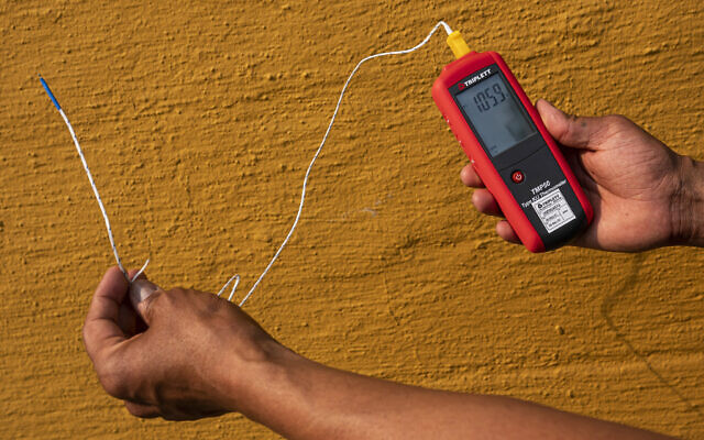 Vivek Shandas, a professor of climate adaptation at Portland State University, takes a temperature reading of almost 106 degrees in downtown Portland, Oregon, on August 12, 2021. (AP Photo/Nathan Howard, File) Vivek Shandas, a professor of climate adaptation at Portland State University, takes a temperature reading of almost 106 degrees in downtown Portland, Oregon, on August 12, 2021. (AP Photo/Nathan Howard, File)