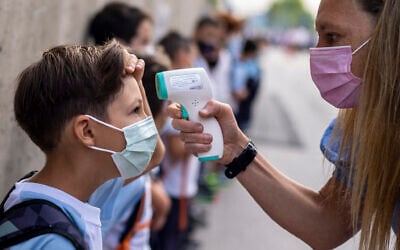 A teacher wearing a face mask checks the temperature of her student at Maestro Padilla school in Madrid, Sept. 7, 2021. (AP Photo/Manu Fernandez, File)