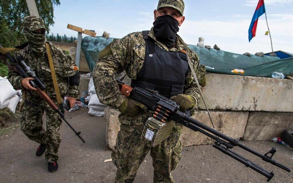 Masked pro-Russian armed militants guard a checkpoint with a Russian national flag on the right, blocking the major highway which links Kharkiv, outside Slovyansk, Ukraine, on May 24, 2014. (AP Photo/Alexander Zemlianichenko)