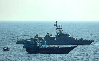 US service members board a stateless fishing vessel transiting international waters in the Gulf of Oman as a rigid-hull inflatable boat and patrol coastal ship USS Chinook (PC 9) sail nearby, Jan. 18, 2022. (US Navy via AP)