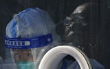 A medical worker wearing protective gear collects a sample from a resident at a coronavirus test site in Xichen District in Beijing, Tuesday, Jan. 25, 2022. (AP Photo/Andy Wong)