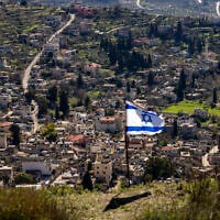 The Palestinian village of Burqa is seen as an Israeli flag is placed in the Jewish West Bank outpost of Homesh, January 17, 2022. (AP/Ariel Schalit)