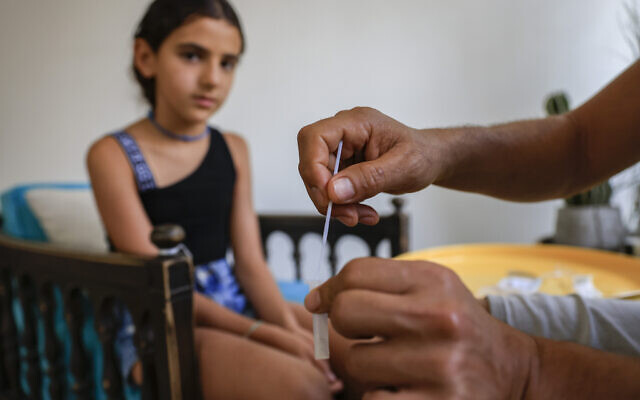 A Jerusalem father tests his daughter with a home rapid test ahead of her first day of school, August 31, 2021. (Olivier Fitoussi/Flash90) A Jerusalem father tests his daughter with a home rapid test ahead of her first day of school, August 31, 2021. (Olivier Fitoussi/Flash90)