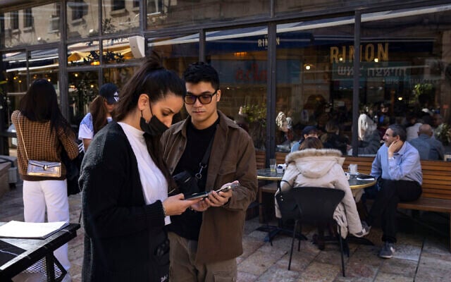Israelis present their Green Pass vaccination certificates at the entrance of a cafe on December 27, 2021. (Olivier Fitoussi/Flash90) Israelis present their Green Pass vaccination certificates at the entrance of a cafe on December 27, 2021. (Olivier Fitoussi/Flash90)