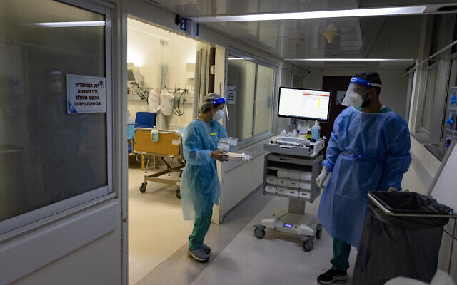 Hadassah Ein Kerem Hospital staff wear safety gear as they work in a coronavirus ward on December 27, 2021. (Olivier Fitoussi/Flash90) Hadassah Ein Kerem Hospital staff wear safety gear as they work in a coronavirus ward on December 27, 2021. (Olivier Fitoussi/Flash90)