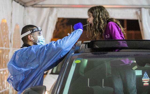 A health care worker takes swab samples from Israelis at a drive-thru testing complex in Modiin, January 6, 2022. (Yossi Aloni/Flash90)