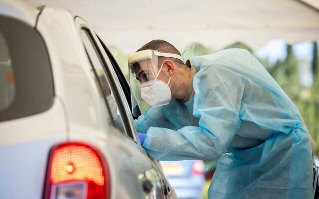 A Magen David Adom health worker takes a swab sample at a drive-thru coronavirus testing complex in Jerusalem, on January 11, 2022. (Yonatan Sindel/Flash90) A Magen David Adom health worker takes a swab sample at a drive-thru coronavirus testing complex in Jerusalem, on January 11, 2022. (Yonatan Sindel/Flash90)