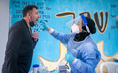 A medical worker takes a COVID-19 rapid antigen test from Israelis, at a testing center in Beit Hashmonai, on January 16, 2022. ( Yossi Aloni/Flash90) A medical worker takes a COVID-19 rapid antigen test from Israelis, at a testing center in Beit Hashmonai, on January 16, 2022. ( Yossi Aloni/Flash90)