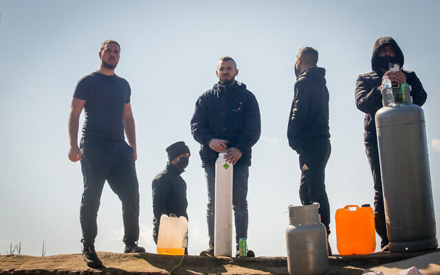 Palestinians with gas cylinders stand on a rooftop of a house being evacuated by Israeli special forces in the East Jerusalem neighborhood of Sheikh Jarrah, January 17, 2022. (Jamal Awad/Flash90)