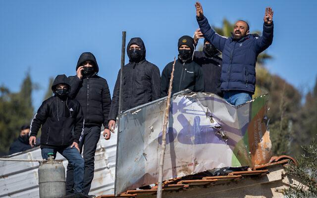 Palestinians with gas cylinders stand on a rooftop of a house being evacuated by Israeli special forces in the East Jerusalem neighborhood of Sheikh Jarrah, January 17, 2022. (Yonatan Sindel/Flash90)