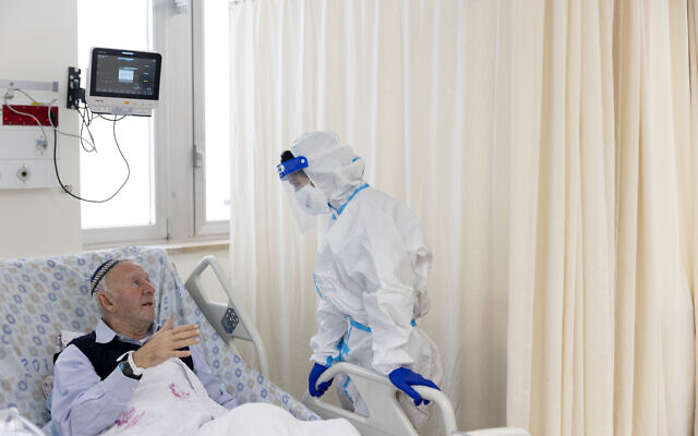 An Ezer Mizion volunteer wearing safety gear visits a patient in the coronavirus ward of Shaare Zedek hospital in Jerusalem, on January 20, 2022. (Olivier Fitoussi/Flash90) An Ezer Mizion volunteer wearing safety gear visits a patient in the coronavirus ward of Shaare Zedek hospital in Jerusalem, on January 20, 2022. (Olivier Fitoussi/Flash90)