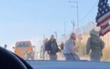 Israeli settlers attack Palestinian cars at a checkpoint in the northern West Bank as an IDF soldier attempts to drive them back on January 26, 2022. (Screen capture: Twitter)