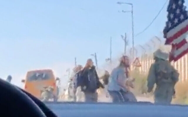 Israeli settlers attack Palestinian cars at a checkpoint in the northern West Bank as an IDF soldier attempts to drive them back on January 26, 2022. (Screen capture: Twitter)
