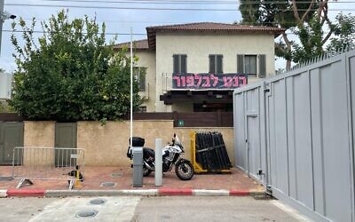 A Ra'anana home bifurcated by a security wall, with a "Bennett to Balfour" sign in Hebrew. January 13, 2022. (Carrie Keller-Lynn/Times of Israel)