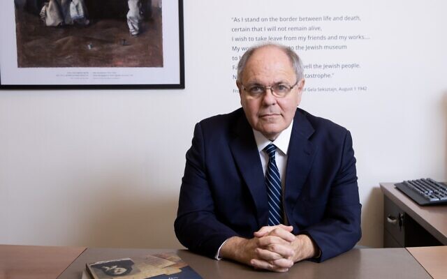 Head of Yad Vashem Dani Dayan in his Jerusalem office, in front of a quote from murdered artist Gela Seksztajn. (Alex Kolomoisky/Yad Vashem)