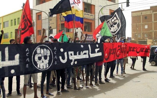 Demonstrators march with a large banner reading in Arabic "[we are] angry" during ongoing protests calling for civilian rule and denouncing the military administration, in the Sahafa neighborhood in Sudan's capital Khartoum on February 20, 2022. (Ebrahim Hamid / AFP)