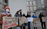 Protesters hold placards demanding sanctions during a rally outside the Ukrainian Ministry of Foreign Affair in Kyiv on February 21, 2022 (Sergei SUPINSKY / AFP)
