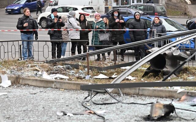 People react standing behind the cordoned off area around the remains of a shell in Kyiv on February 24, 2022 (Sergei SUPINSKY / AFP) People react standing behind the cordoned off area around the remains of a shell in Kyiv on February 24, 2022 (Sergei SUPINSKY / AFP)