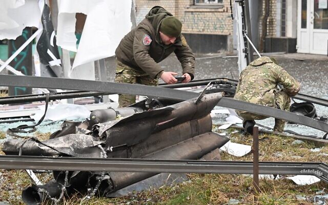 Police and security personnel inspect the remains of a shell in a street in Kyiv, on February 24, 2022. (Sergei Supinsky/AFP)