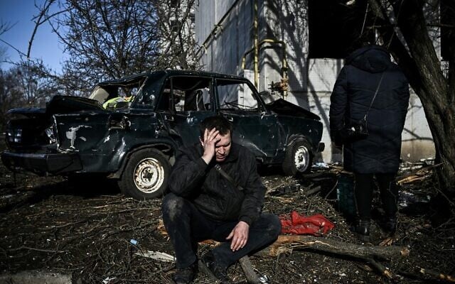 A man sits outside his destroyed building after bombings on the eastern Ukraine town of Chuguiv, on February 24, 2022. (Aris Messinis/AFP)