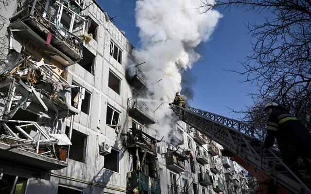Firefighters work on a fire on a building after bombings on the eastern Ukraine town of Chuguiv on February 24, 2022, as Russian armed forces invade Ukraine from several directions, using rocket systems and helicopters to attack Ukrainian position in the south, the border guard service said. (Aris Messinis / AFP)
